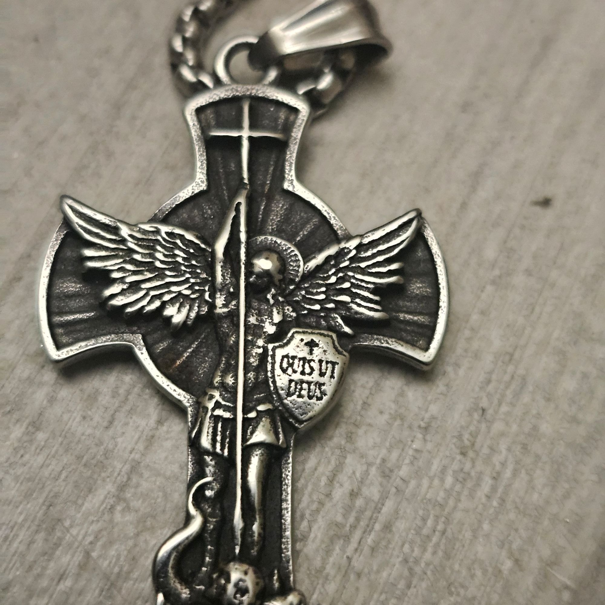A silver cross pendant of the Archangel Michael with the shield Quis ut Deus